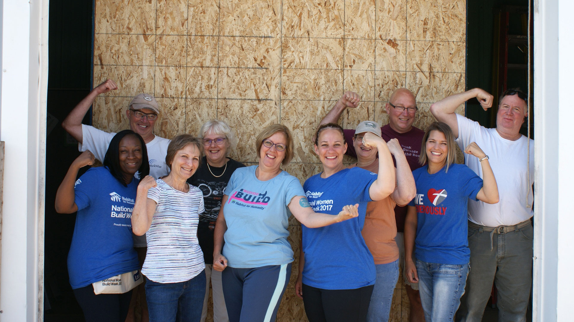 Habitat for Humanity volunteers are flexing their biceps showing they are strong.