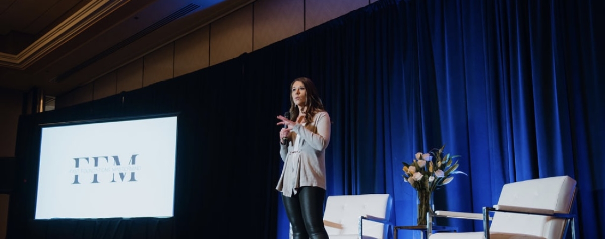 Photo of Julie Menden on stage speaking at an event.