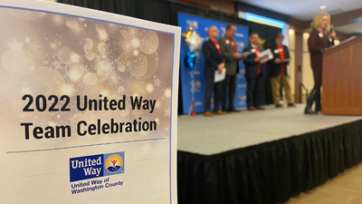 Close up image of the 2022 United Way Team Celebration program with volunteers in the background.